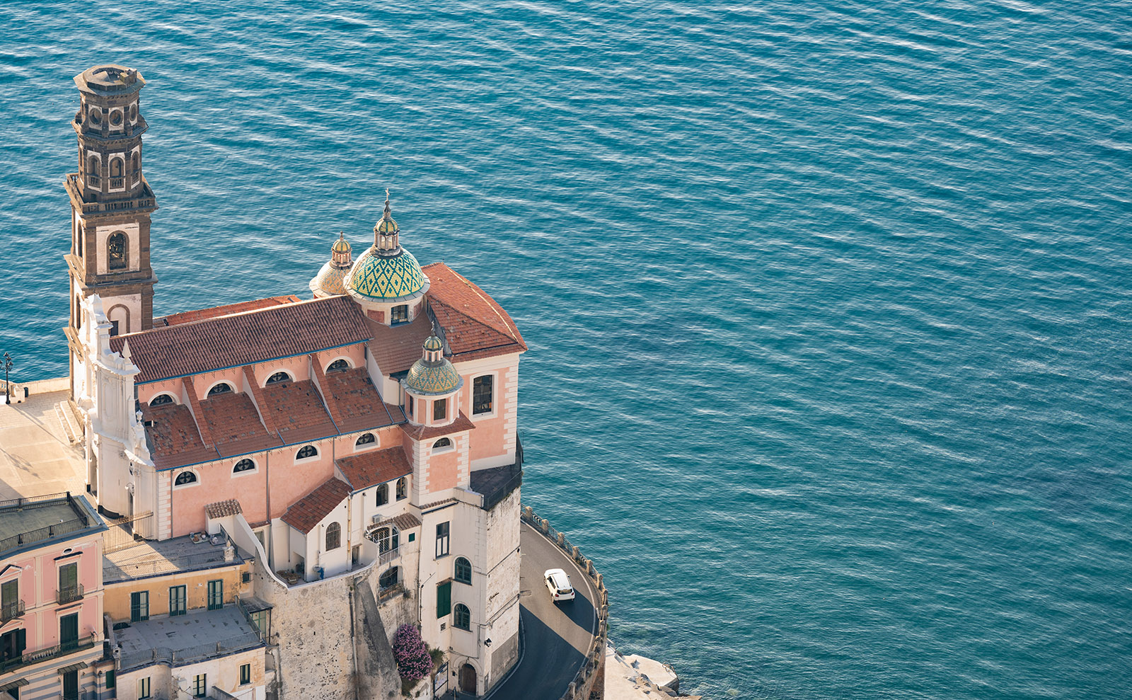 a pink stone castle overlooking the blue sea