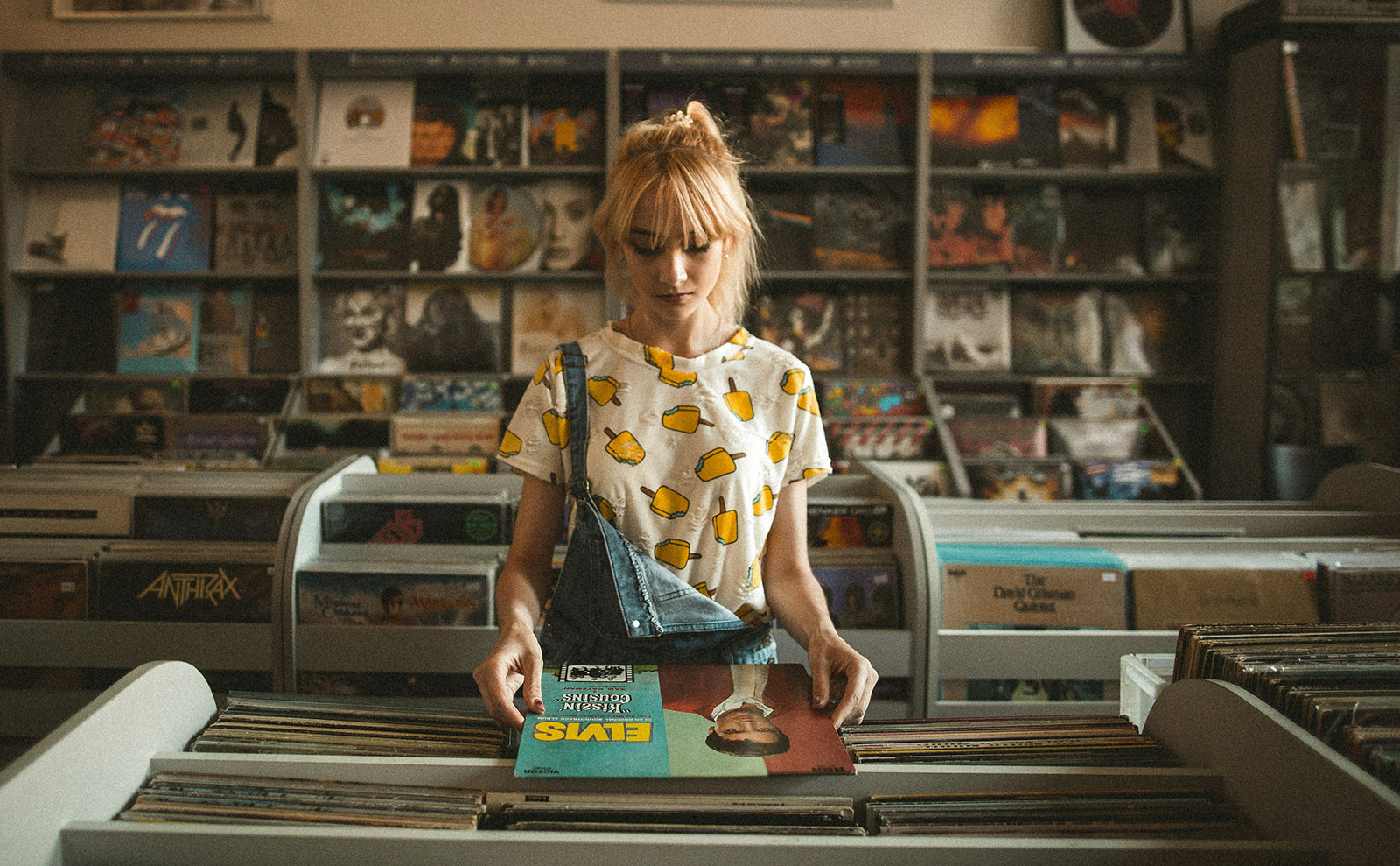 a young blond girl standing a record shop with a vintage lp in her hands