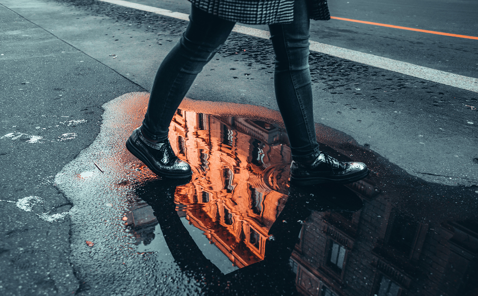 black pavement with the reflection of a building in a puddle of water